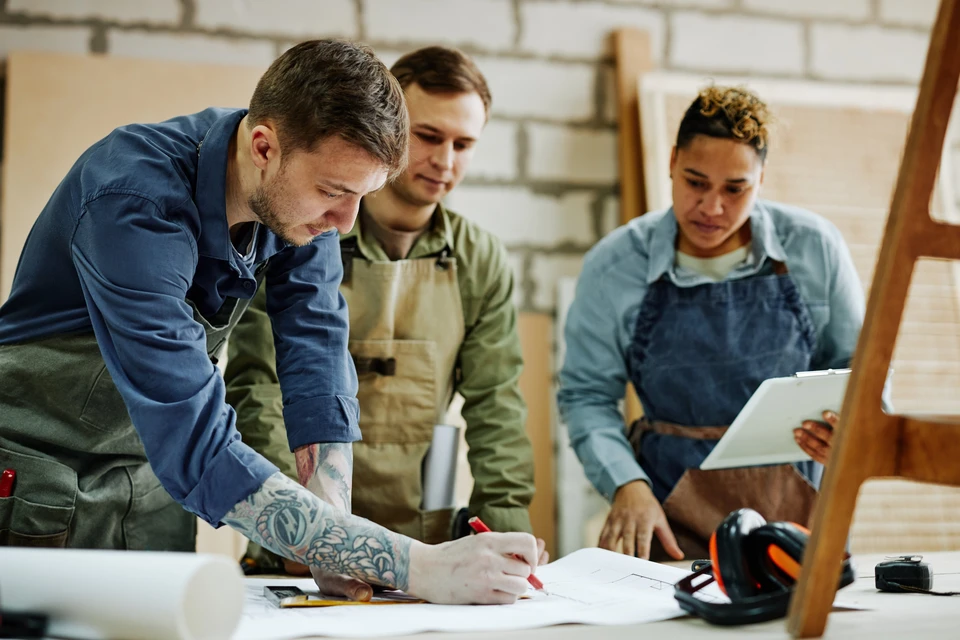 Portrait chaleureux d'artisans modernes discutant de la conception de meubles dans un atelier de menuiserie
