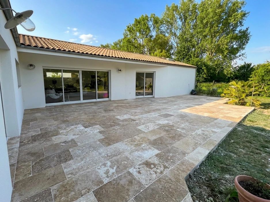 Terrasse extérieure d'une villa plain-pied, dallage en travertin format opus romain, pose à joint fin