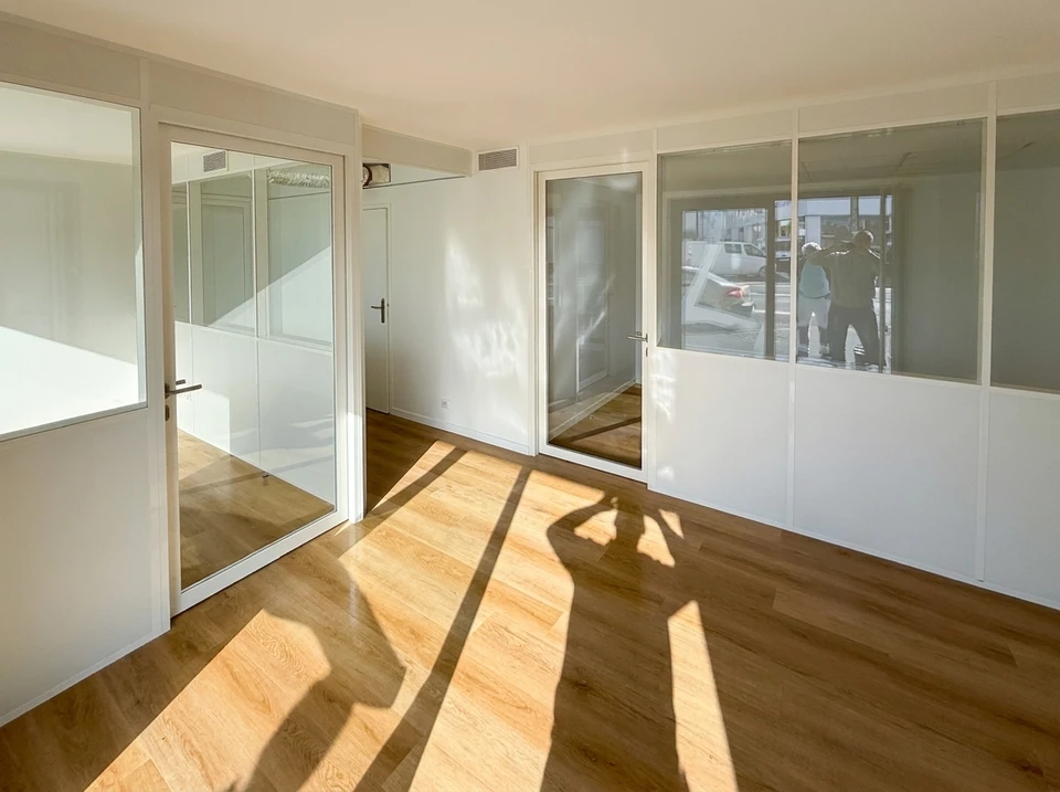 Intérieur d'un chantier de rénovation où un artisan installe un parquet contrecollé sur une chape avec colle