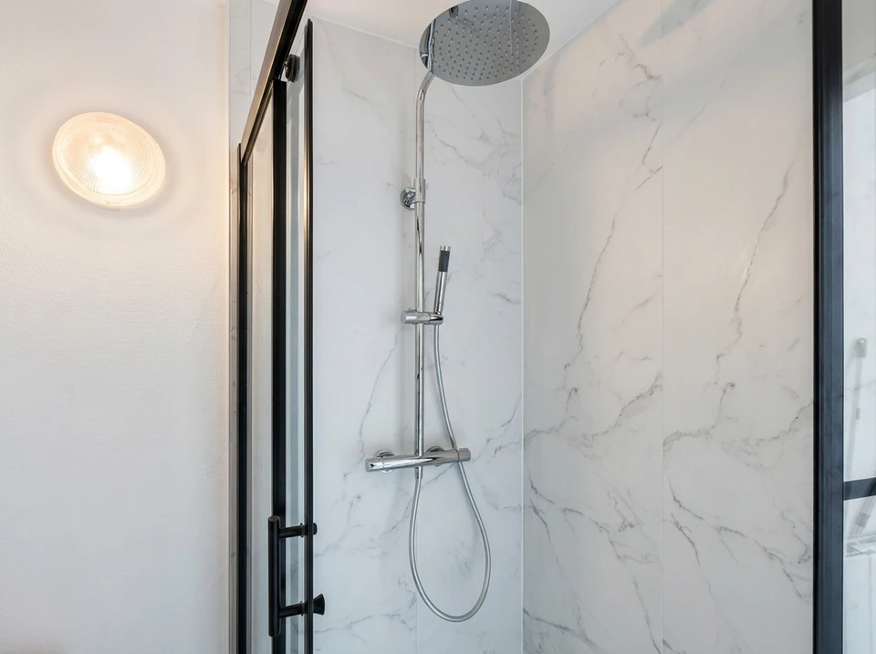 Salle de bain moderne avec douche à l'italienne vitrée, carrelage gris anthracite effet béton sur les murs, vasque blanche encastrée dans meuble suspendu noir, robinetterie chromée contemporaine, serviette violette sur porte-serviettes