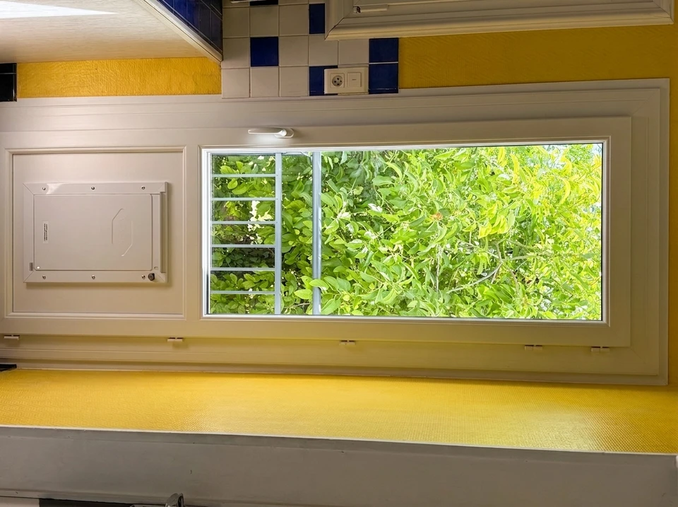 Intérieur, mains d'homme appliquant un enduit ou colle sur mur avec spatule métallique tout en pulvérisant produit depuis pulvérisateur à pression jaune et noir