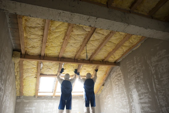Pièce vide en cours de rénovation avec échelle en bois, pots de peinture colorés et rouleau au sol