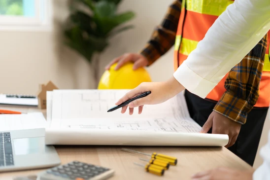 Deux professionnels collaborent autour d'un écran d'ordinateur affichant un planning de projet avec timeline, tâches assignées et notifications