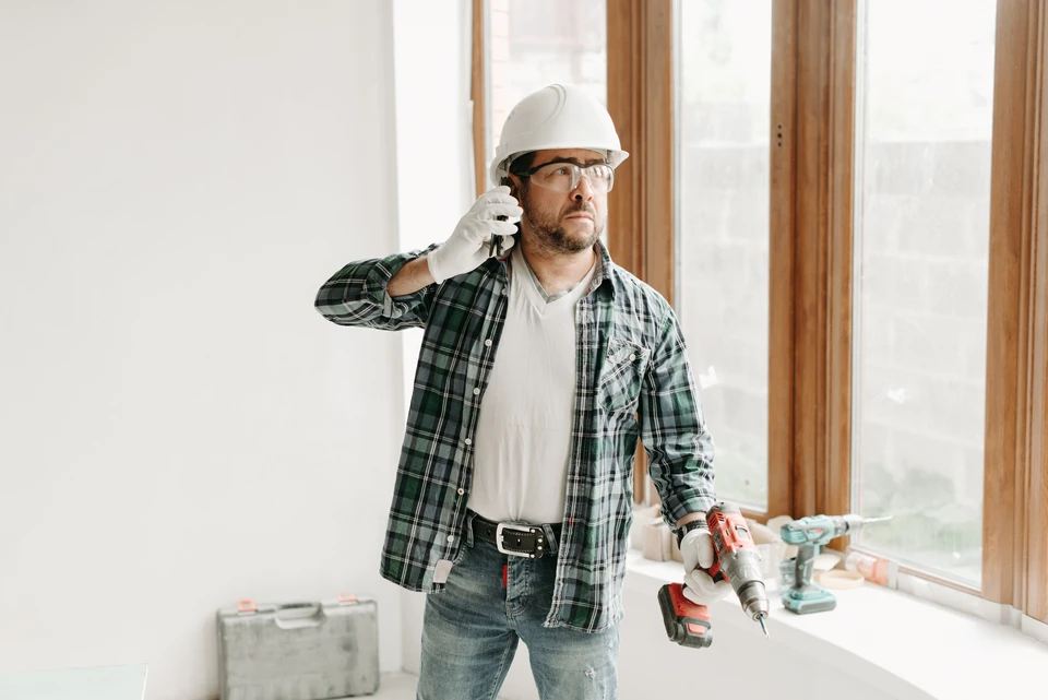Homme en t-shirt bleu travaillant sur une porte intérieure blanche, utilisant un tournevis pour ajuster ou réparer la serrure